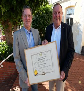 Ämterwechsel beim Rotary Club Amrum: Präsident Cornelius Bendixen reicht die Charterurkunde an seinen Nachfolger Frank Timpe weiter
