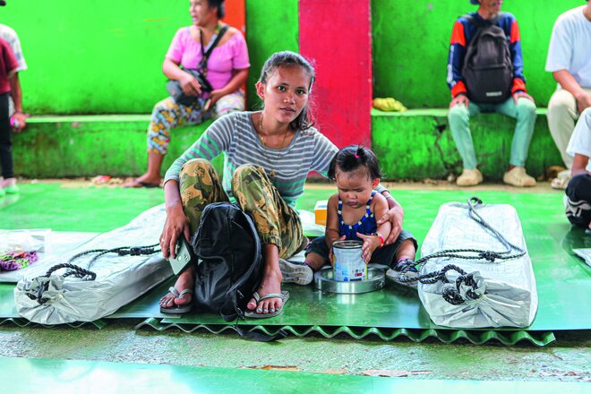 Ihnen wird wieder Hoffnung gespendet: Eine junge Mutter sitzt mitihrem Kleinkind auf den Dachlatten, die für sie bestimmt sind