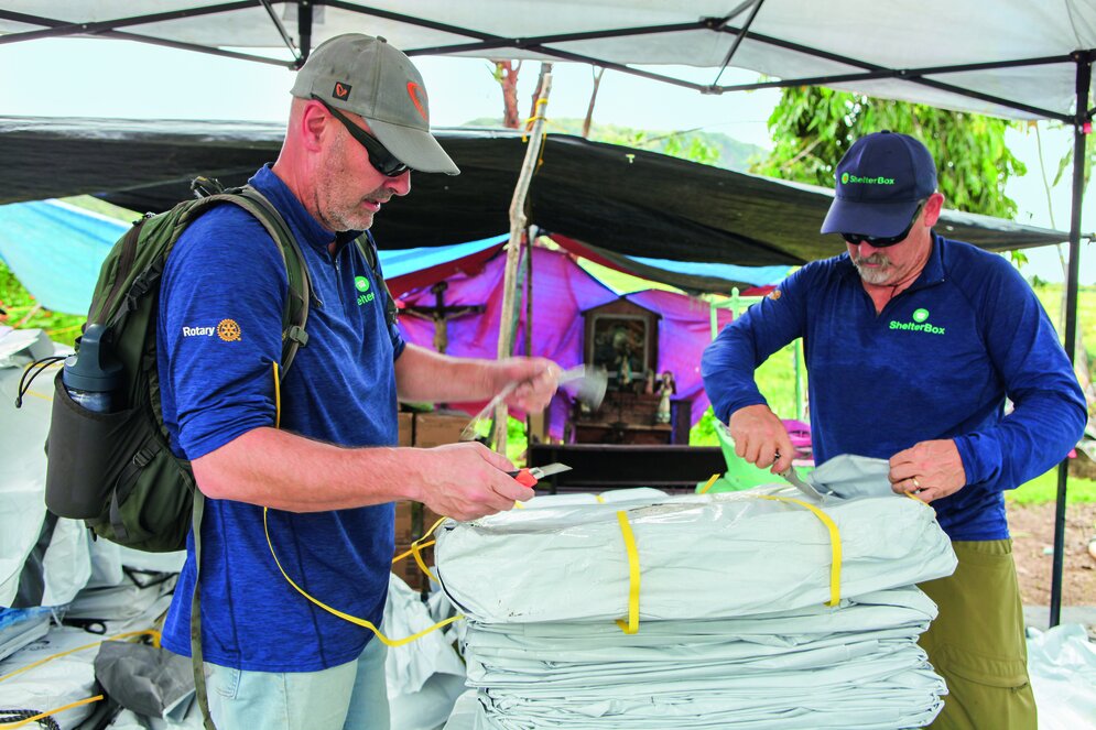 Dave Ray und ­Brian Glenn ­packen Planen aus, die in Kürze in Binabag verteilt werden sollen