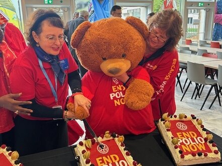 Christine Büring und Sabina Gärtner-Nitsche mit dem Polio-Bären vor einem Kuchenbüfett mit leckeren Küchlein geschmückt mit End-Polio-Now-Logo