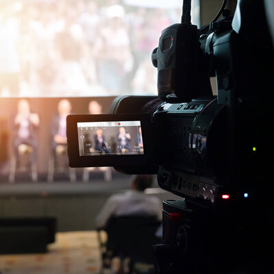 der Blick aus dem Publikum, teilweise durch ein Kameradisplay, auf ein Podium