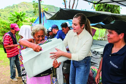 Eine ältere Frau in Binabag bekommt Hilfsgüter von der Rotarierin Mildred Vitangcol überreicht 