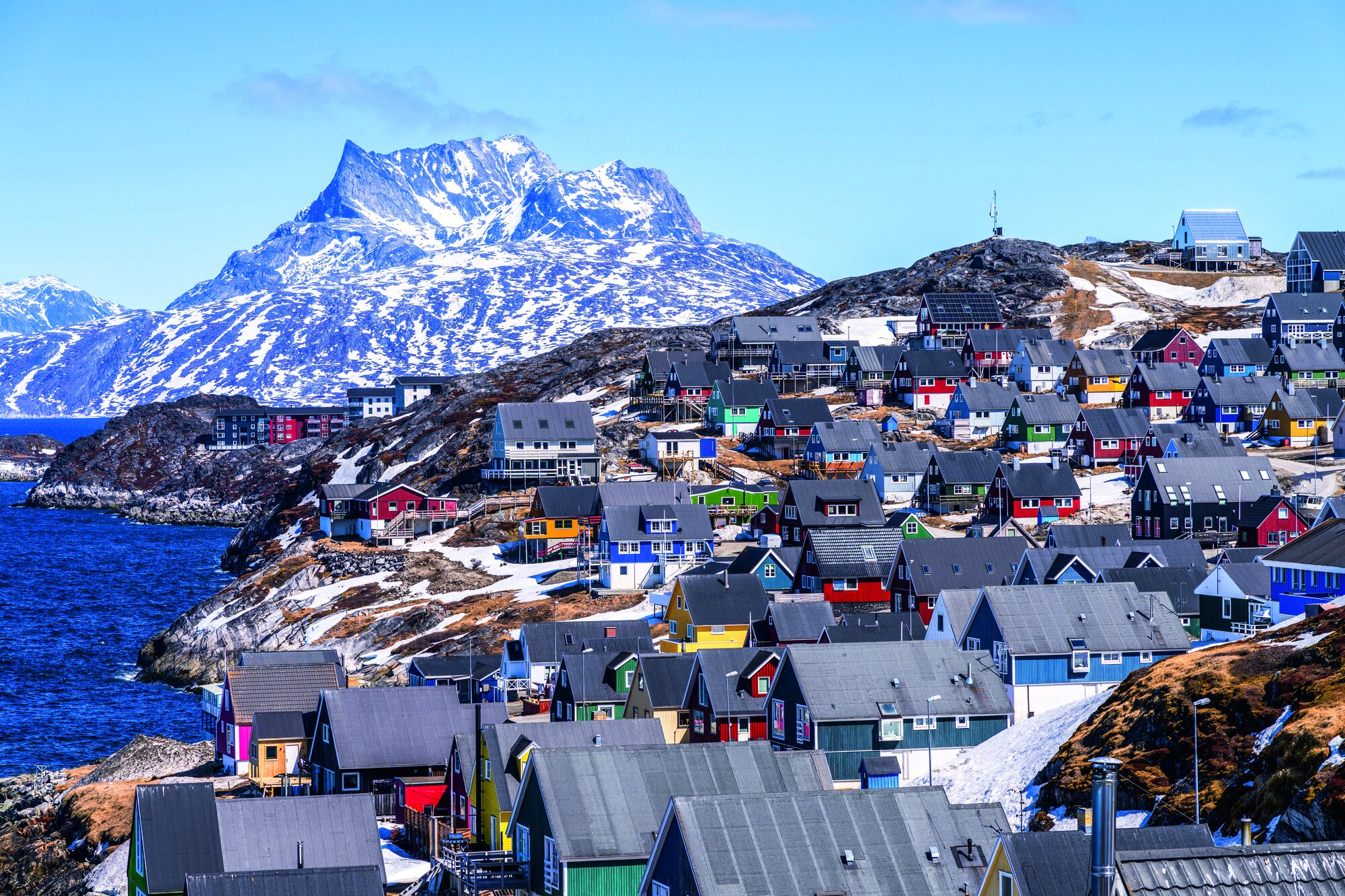 Malerischer Blick auf farbenfrohe Häuser an der Küste von Nuuk/Grönland mit dem Berg Sermitsiaq im Hintergrund