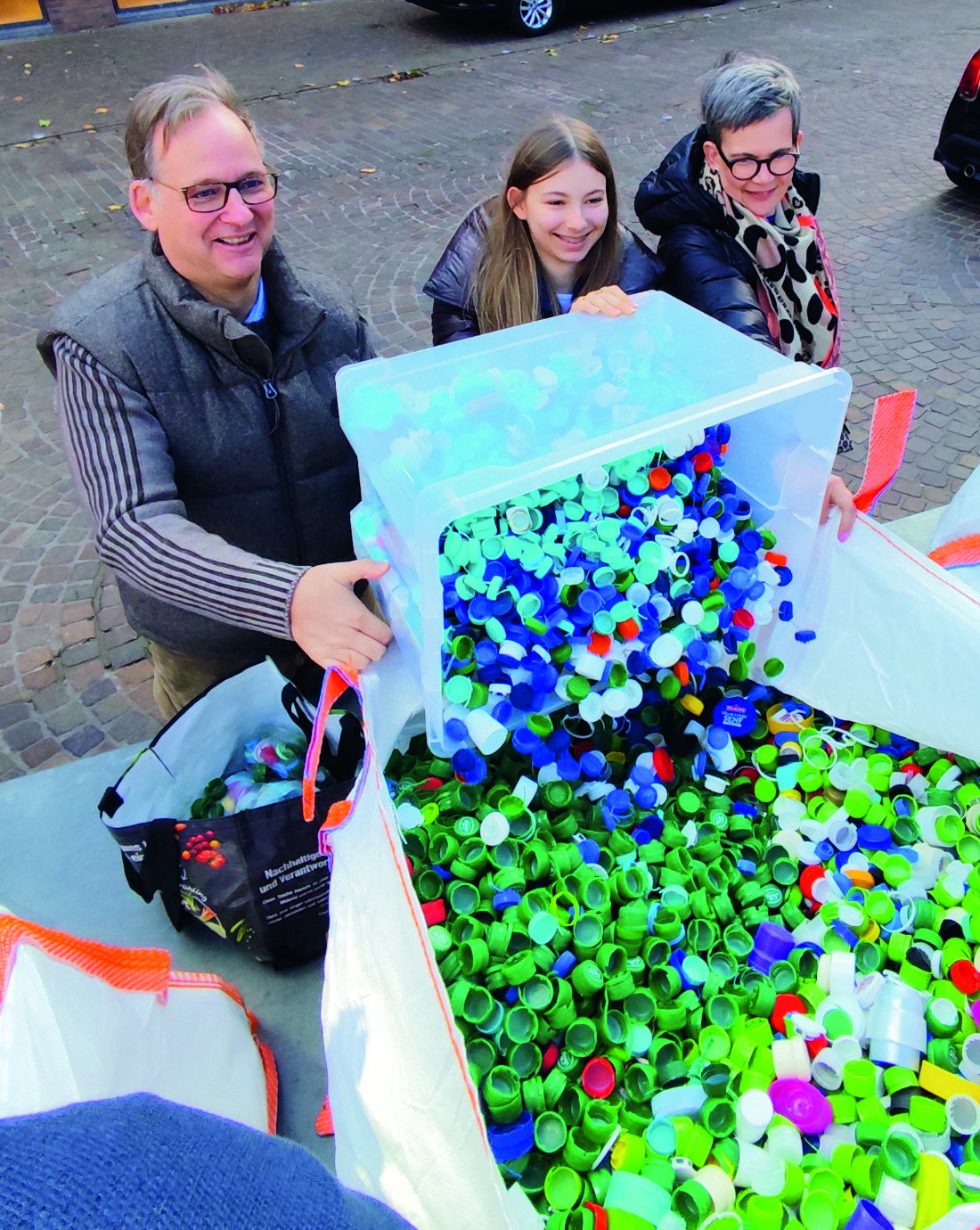 Hendrik Bönemann schüttet mit Tochter Julia und Frau Iris Hunderte Flaschendeckel in einen der Sammelsäcke Hendrik Bönemann schüttet mit Tochter Julia und Frau Iris Hunderte Flaschendeckel in einen der Sammelsäcke